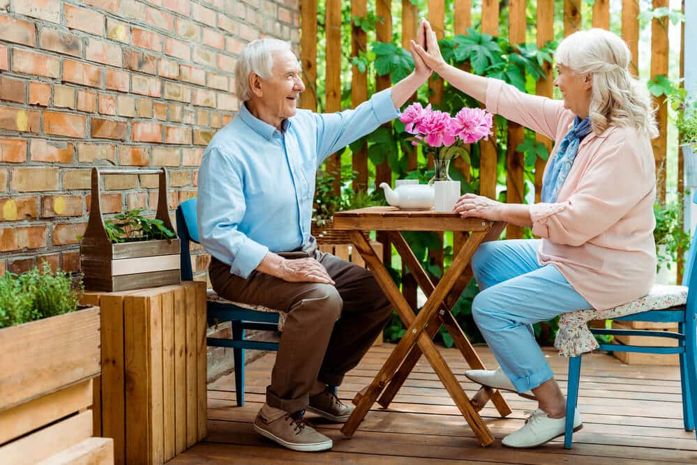 An elderly couple at Hampton Manor in Ocala, Florida, giving each other a high five.