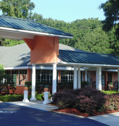 An orange building with a white roof and bushes.