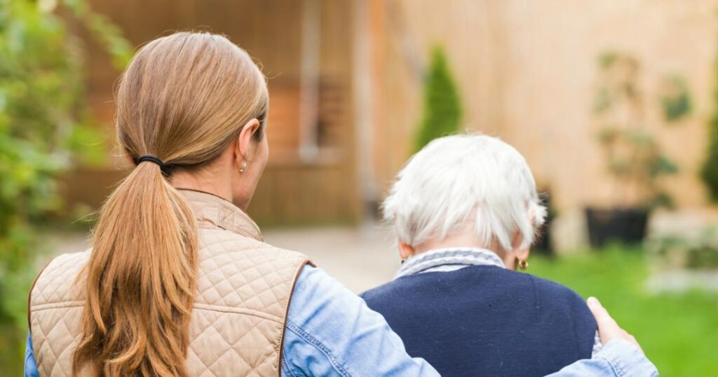 A woman is walking with an elderly woman in an assisted living facility.