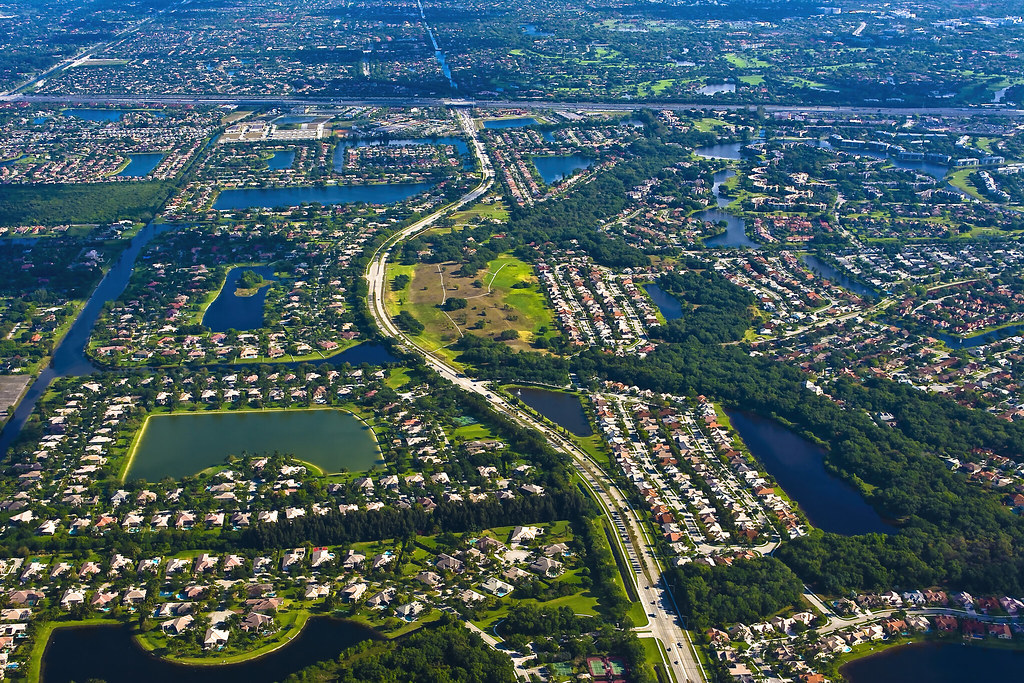 Aerial view of a suburban landscape in Florida, with numerous houses, roads, and scattered bodies of water, displaying a grid-like pattern of streets and greenery—ideal for planning future communities while considering assisted living costs.